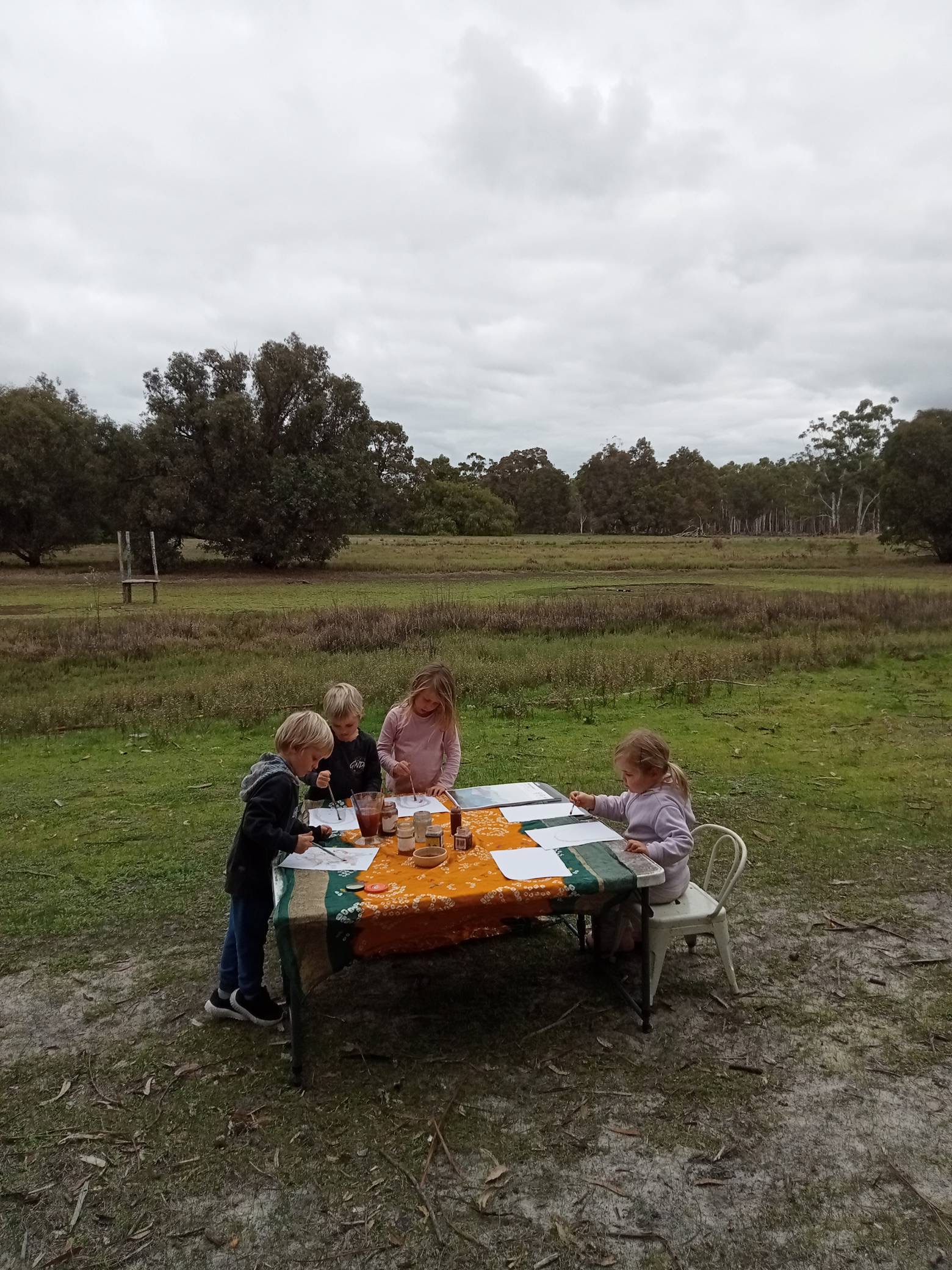 Children working at an outdoor table in the wide landscape