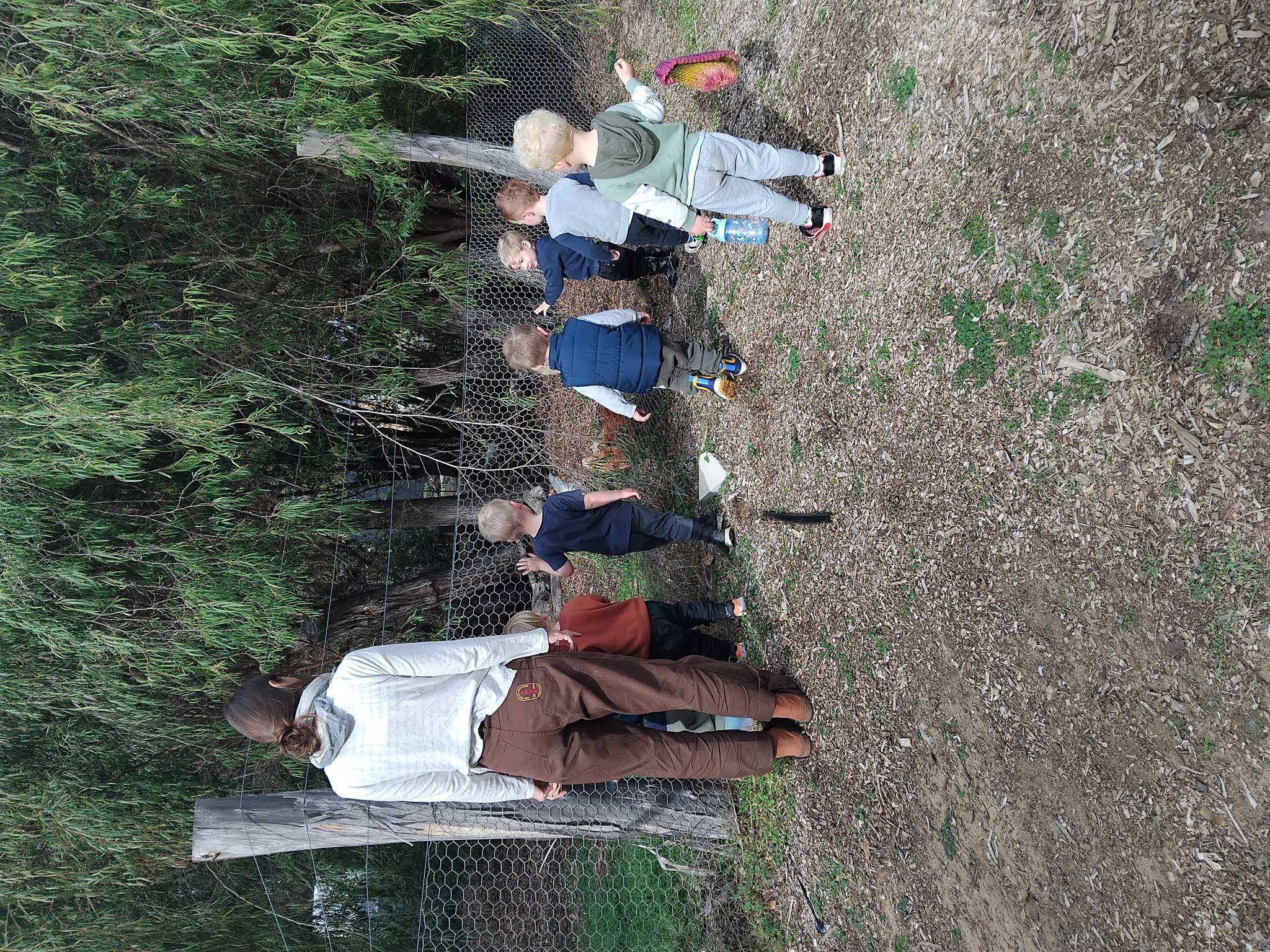 Educator and children investigating along the garden fence